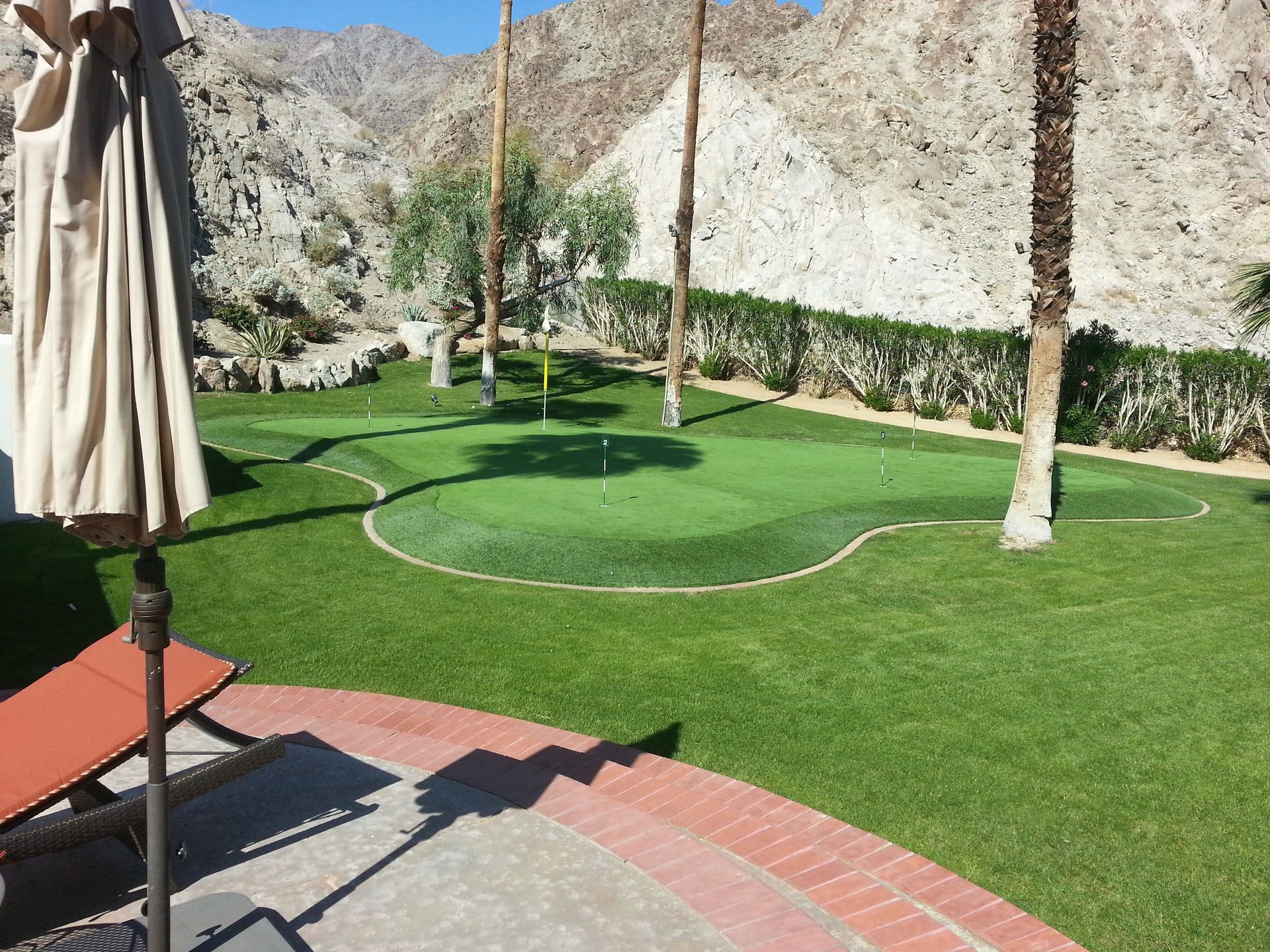 Putting green and flagstick against open desert sky